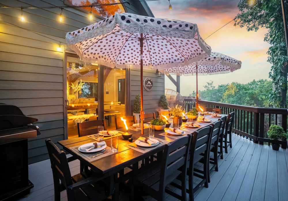 Long sunset dinner table on the cabin deck under polka-dot umbrellas
